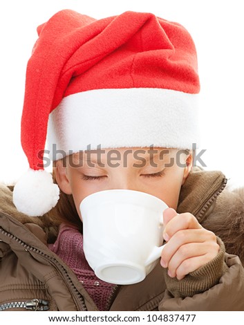 Beautiful little girl in warm winter jacket and red Christmas hat drink tea, isolated on white background.