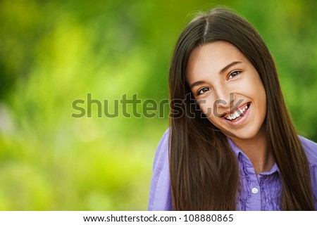 Beautiful smiling teenage girl, against green of summer park.