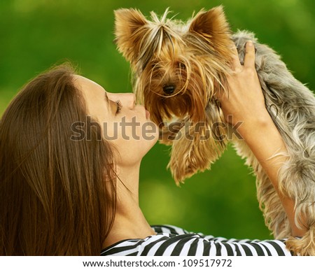 Young beautiful woman with Yorkshire Terrier, against green of summer park.