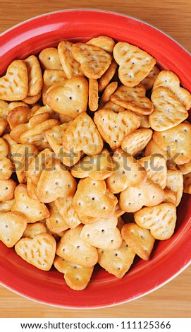 Red plate of cookies on wooden table.