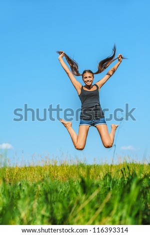 Portrait of young beautiful woman jumps high into sky, on green background summer nature.