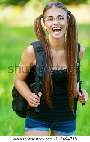 Beautiful dark-haired happy young woman with box pack, against background of summer green park.