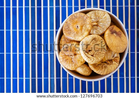 Plate with dried figs, on blue bamboo tablecloth.