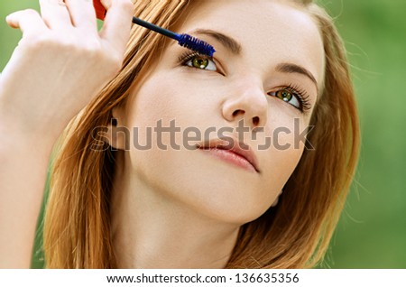 Beautiful young woman with bare shoulders eyes colors, against green of summer park.