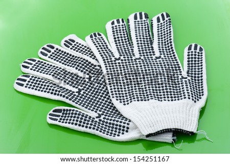 Pair of work gloves lie on green glossy table.
