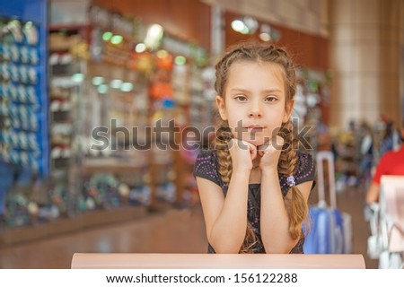 Little beautiful girl in airport duty-free shops in background.