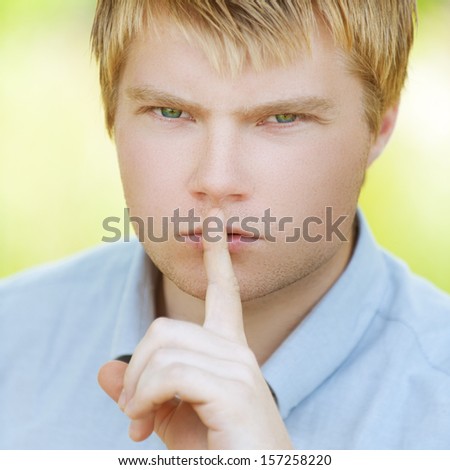Young man put finger to lips and called for silence.