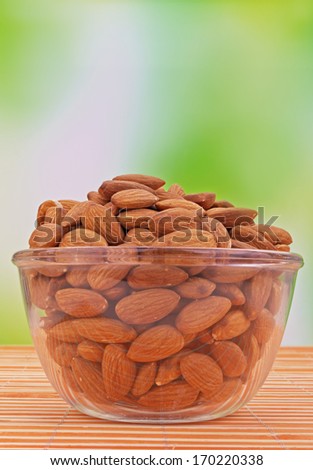 Almonds in pink striped orange plate on bamboo napkin.