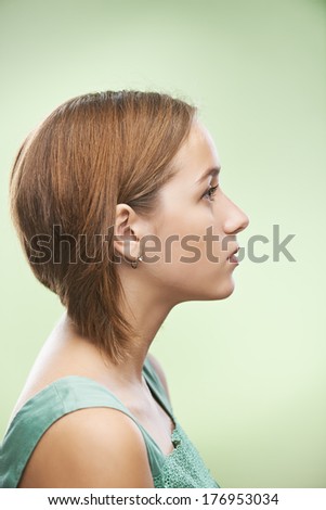 Profile of beautiful young woman, on green background.