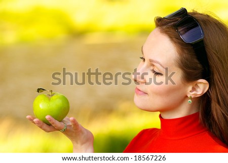 Young woman in red polo-neck holds green apple.