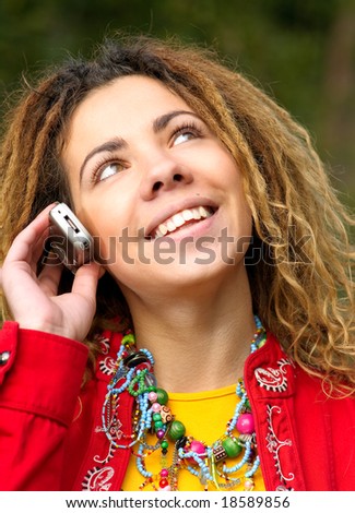 Young woman in red jacket and dreadlocks talks on cellular telephone.