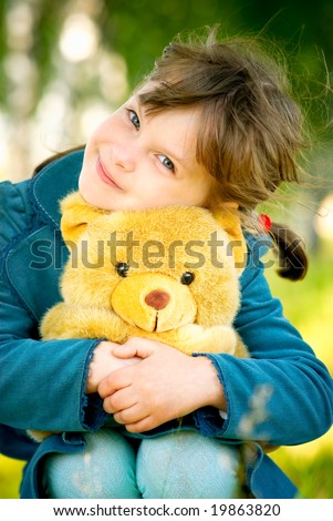 Pretty child embraces toy teddy bear.