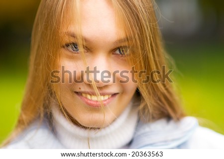 Young woman with long direct hair smiles against nature.