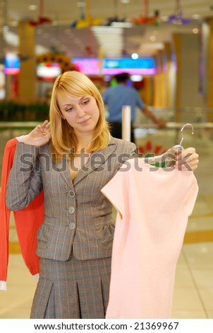 The young beautiful woman in doubt - what blouse to buy?