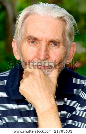 Elderly man with grey-haired beard close up against personal plot.