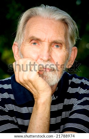 Elderly man with grey-haired beard close up against personal plot.