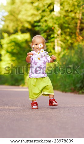 The small child with florets goes on a wood path.