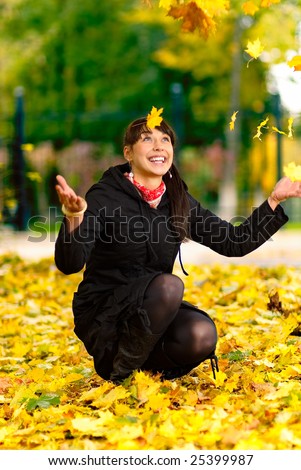 Beautiful girl throws yellow leaves in air and laughs.