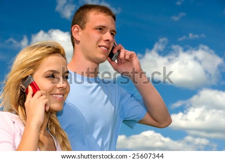 Young beautiful people talk on cellular telephone against dark blue sky to clouds.