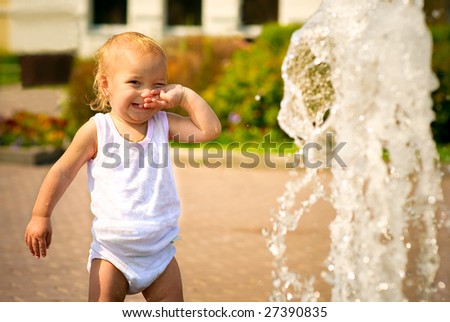 Small child wipes person on whom water from fountain has got.