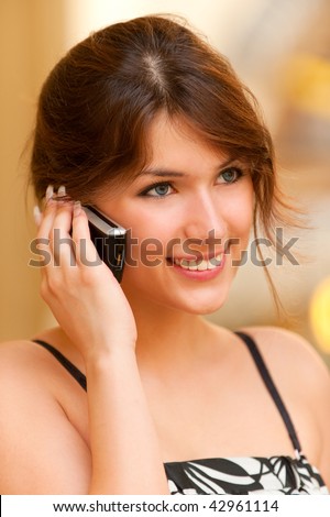 Charming young woman speaks by mobile phone and smiles.