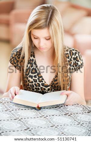 Girl-student reads book in spacious room.