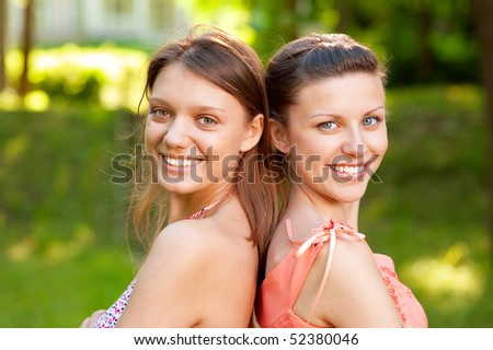 Young women laugh on field in summer.