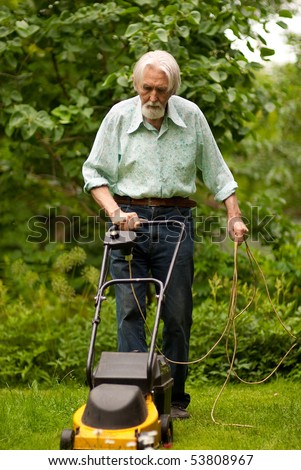 Pensioner mows grass lawn-mower on personal plot.