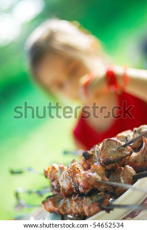 The little girl sits and thinks: it is necessary to eat a shish kebab or it is not necessary?..