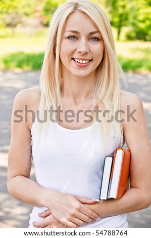 Smiling girl-student with textbook against summer nature.