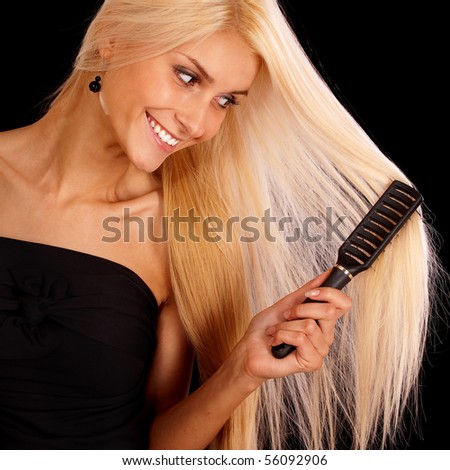 Nice young woman combs hair and smiles, it is isolated on black background.
