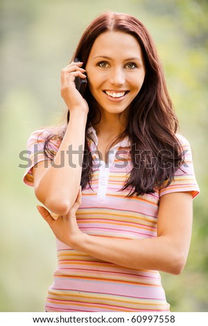 Young smiling woman speaks by mobile phone.