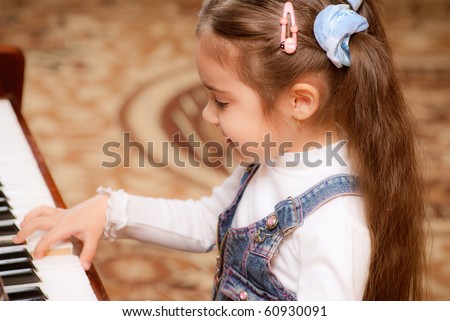 Small dark-haired girl plays piano in educational class.