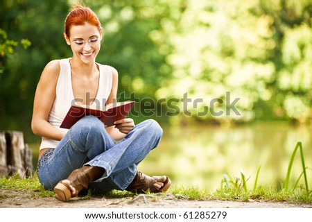 portrait of beautiful red-haired student with book outdoors