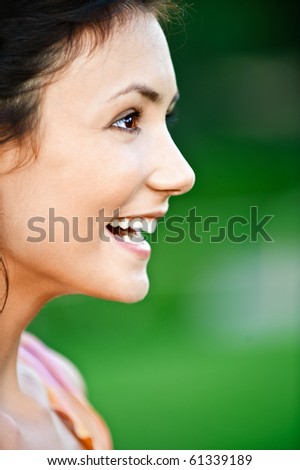 Portrait of beautiful laughing girl close up in profile, on green background.