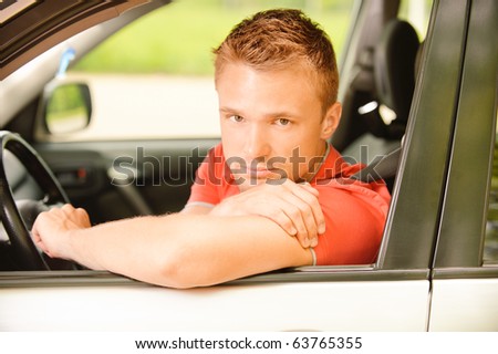 Young man-driver in red clothes at wheel car.
