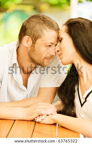 Young couple sit at little table in summer cafe.
