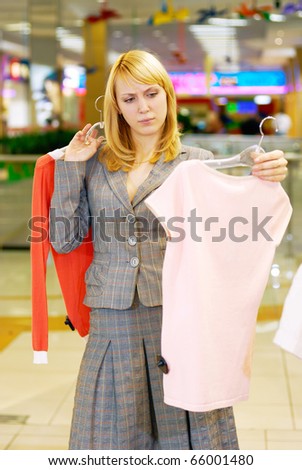 The young beautiful woman in doubt - what blouse to buy?