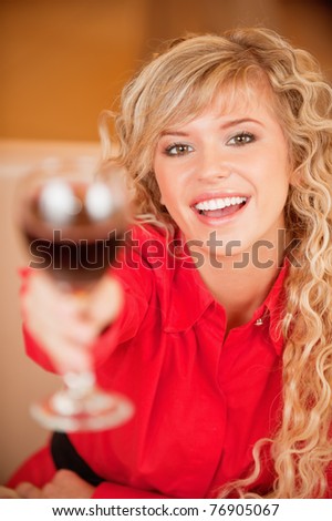 Charming smiling young woman in red clothes with red wine glass sits at magnificent restaurant.