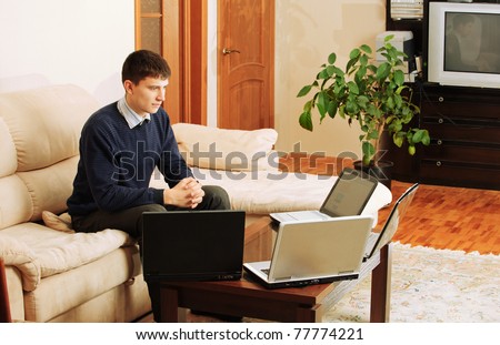 Young charming fair-haired man works on portable computers.