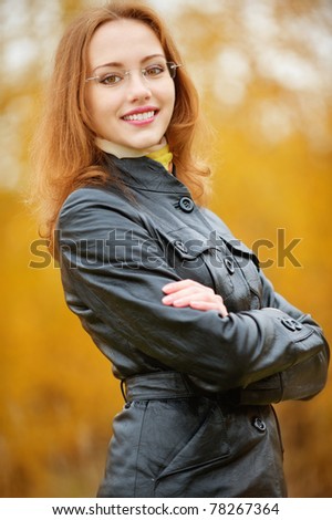 Young smiling girl-student in glasses close up against yellow autumn nature.