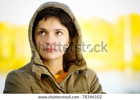 Girl in hood in autumn about wood lake.