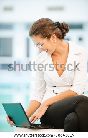 Young beautiful laughing business woman works on laptop.