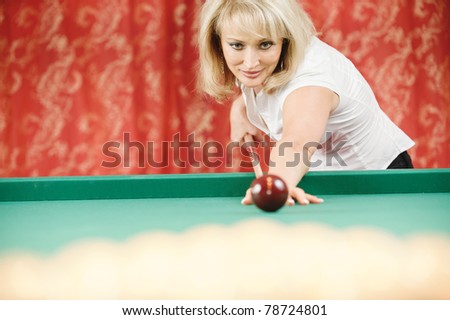 Mature beautiful woman plays billiards in room.