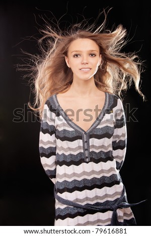 Wind blows hair of young beautiful woman, it is isolated on black background.