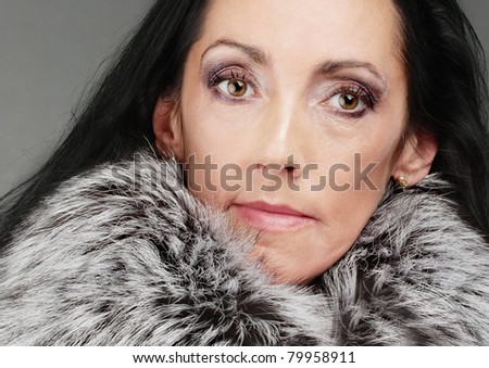 Portrait of beautiful elderly dark-haired woman in clothes with fluffy fur collar.