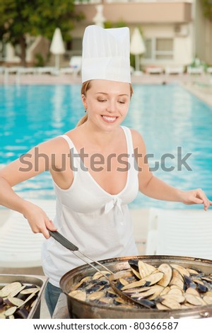 Young beautiful woman cooks food about summer pool on resort.