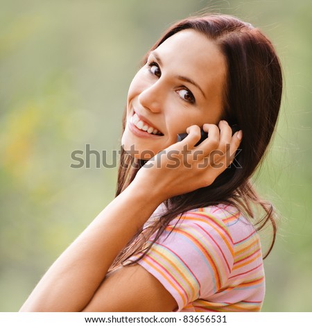 Young smiling woman speaks by mobile phone.