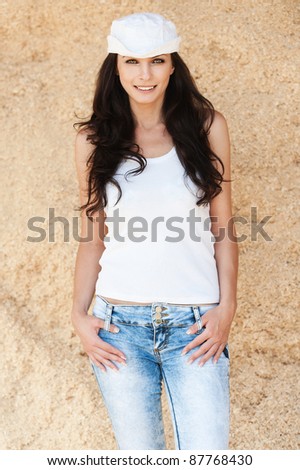 slender long-haired brunette portrait white cap jeans hands pockets