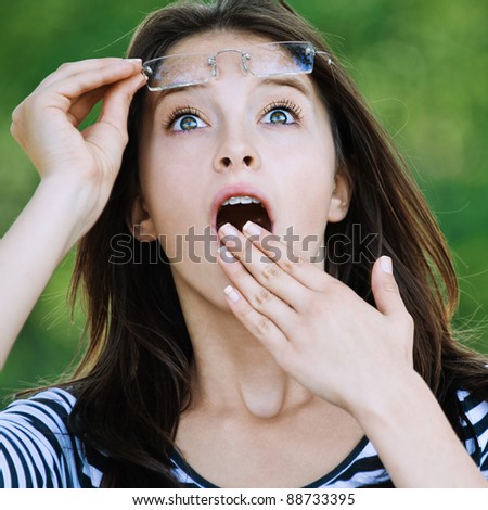 cute young woman looking up surprised raised glasses covers mouth his hand